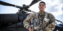 Soldier standing in front of a AH-64 Apache helicopter