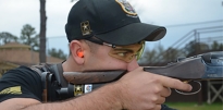 A Soldier aims down the sights of a shotgun.